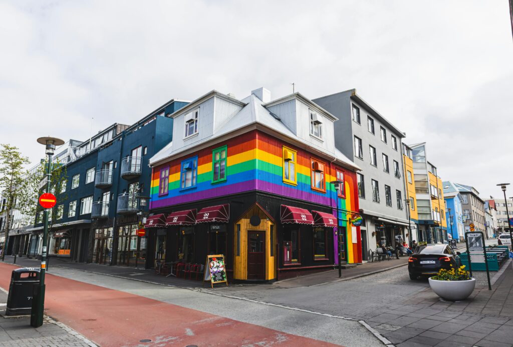 Vibrant rainbow building on a Reykjavík street corner, showcasing LGBTQ inclusivity.