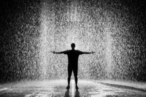 My Personal Gay Stories A person joyfully standing in the rain with arms wide open in a dramatic black and white scene.