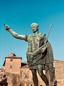 A grand statue of Julius Caesar in Rome, Italy, with historical buildings in the background.